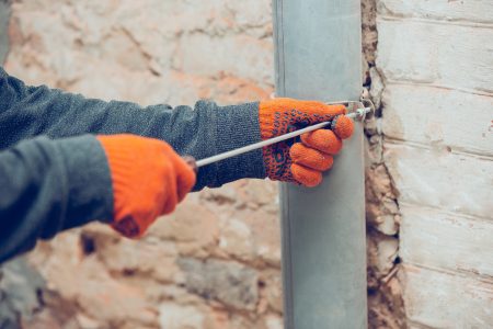 Closeup of repairman in uniform, professional builder working using construction equipment. Process of building, apartment renovation, repairing, building. Sawing, connecting, cutting, preparing.